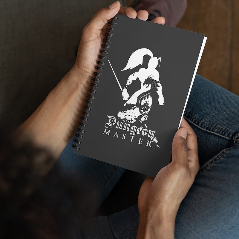Person holding a notebook with 'Dungeon Master' design on the cover