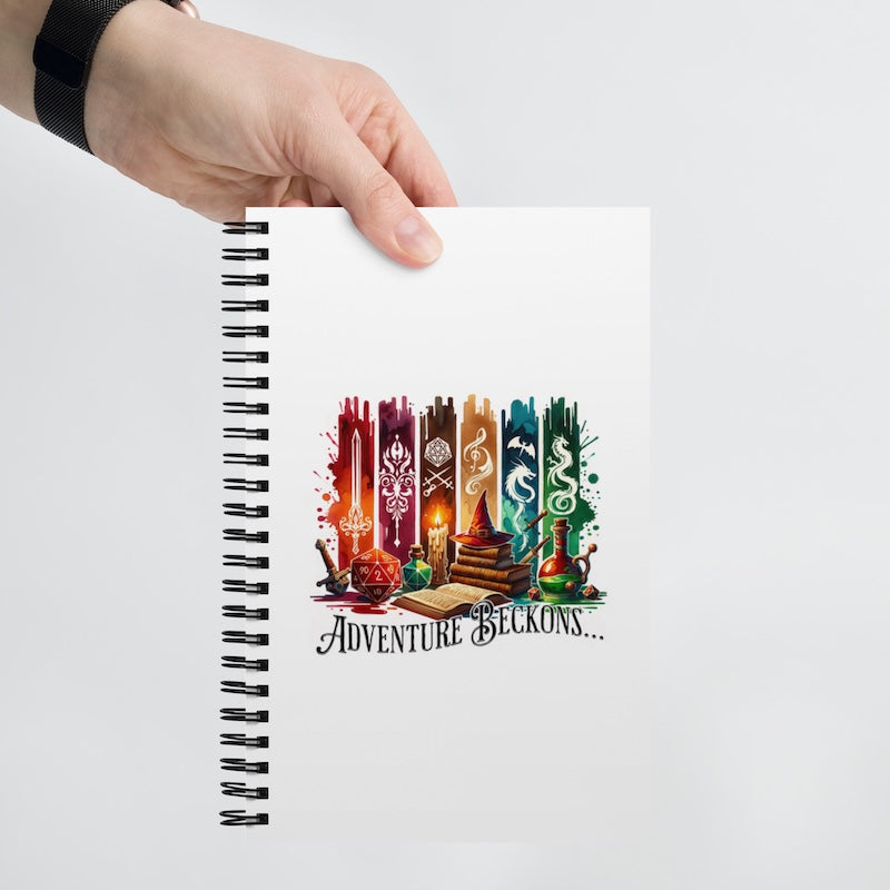Notebook with 'Adventure Beckons' design held by a hand on a white background
