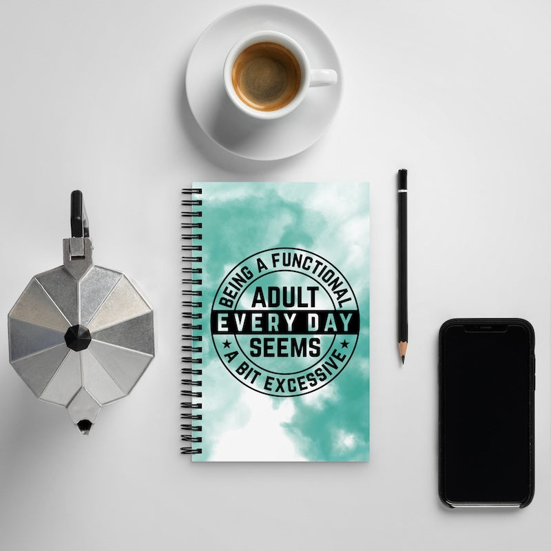 Notebook with a humorous quote, coffee cup, phone, and pencil on a light gray background
