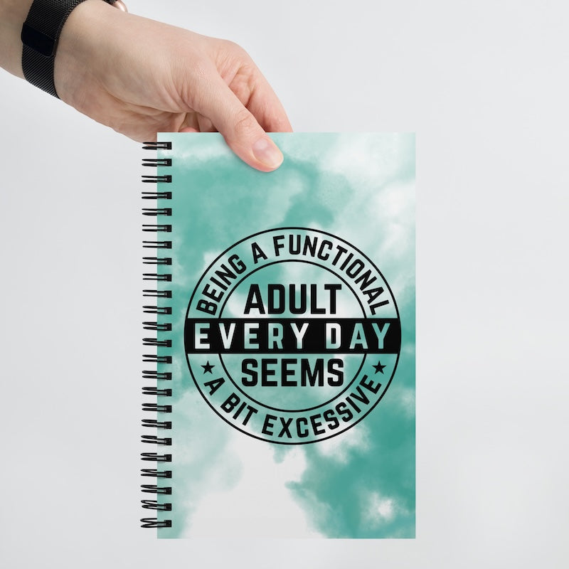 Notebook with a humorous quote on the cover held by a hand against a light background