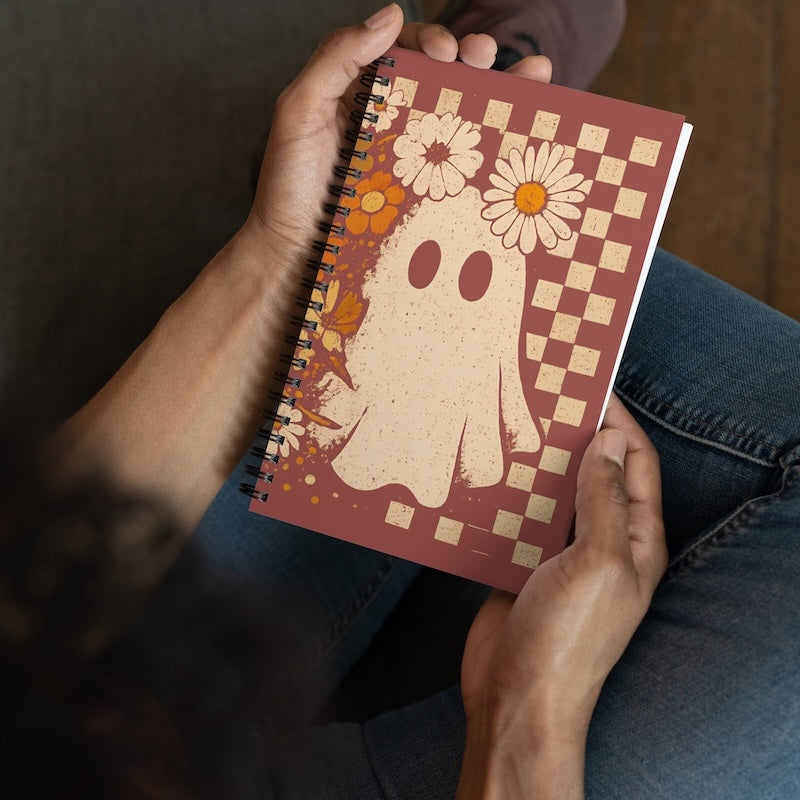 Notebook with ghost and floral design held by a person