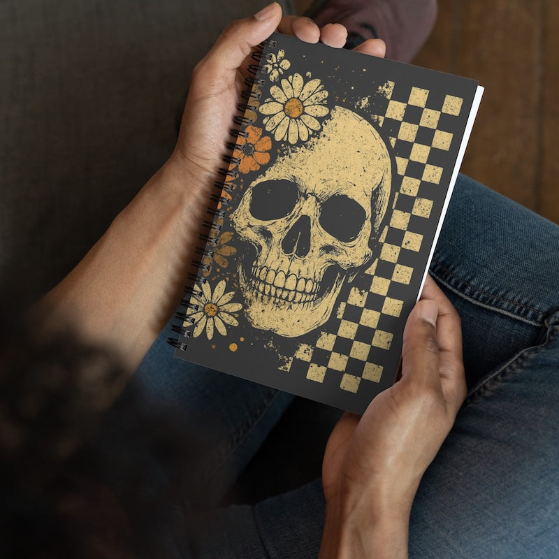 Notebook with skull and floral design held by a person