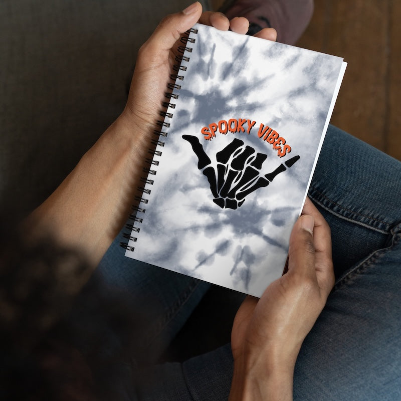 Notebook with 'Spooky Vibes' design held by a person