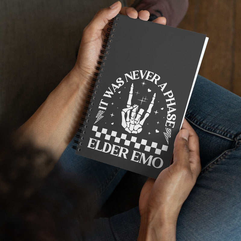 Person holding a notebook with 'It Was Never A Phase Elder Emo' design.
