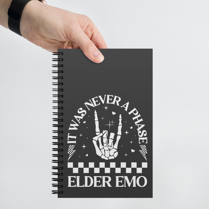 Notebook with a hand holding it, featuring text and a hand sign on a gray background