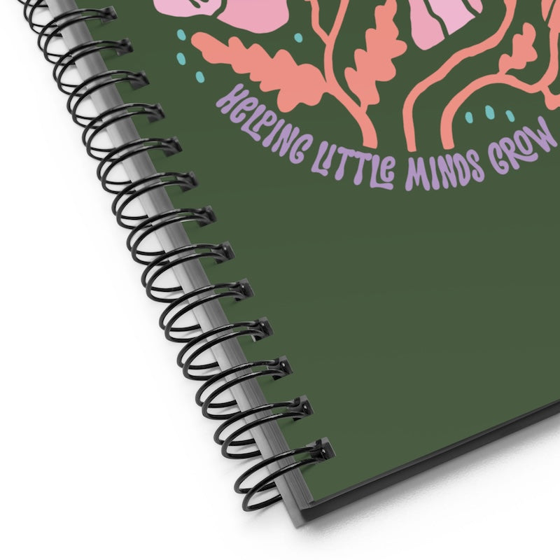 Spiral-bound notebook with floral design and 'Helping Little Minds Grow' text on a green background