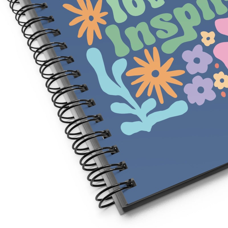 Spiral-bound notebook with colorful floral designs and text on a blue background