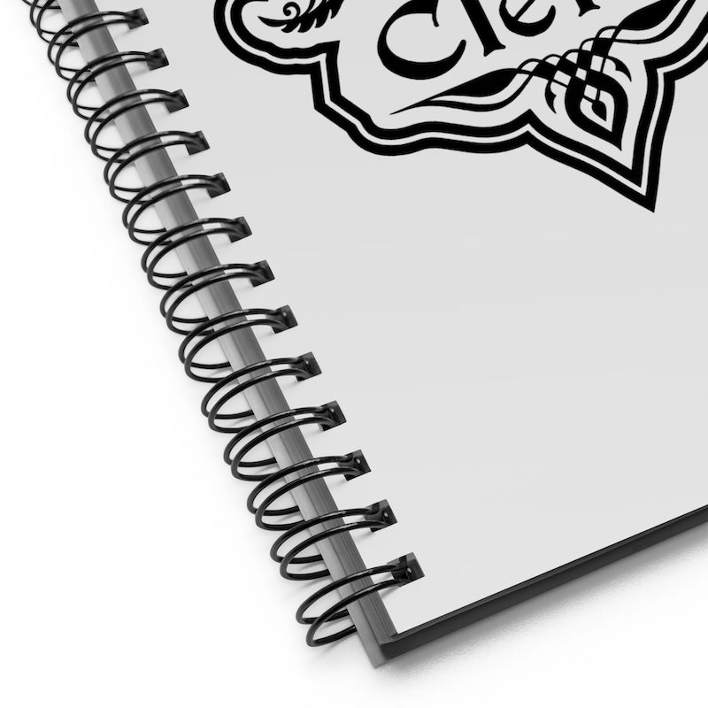 Spiral-bound notebook with decorative emblem on a white background