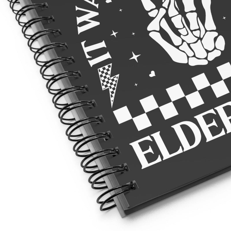 Spiral-bound notebook with skeleton hands and text design on a black background