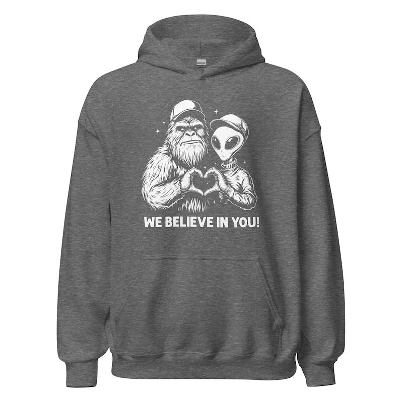 Gray hoodie with alien and creature design and 'We Believe In You!' text on a white background