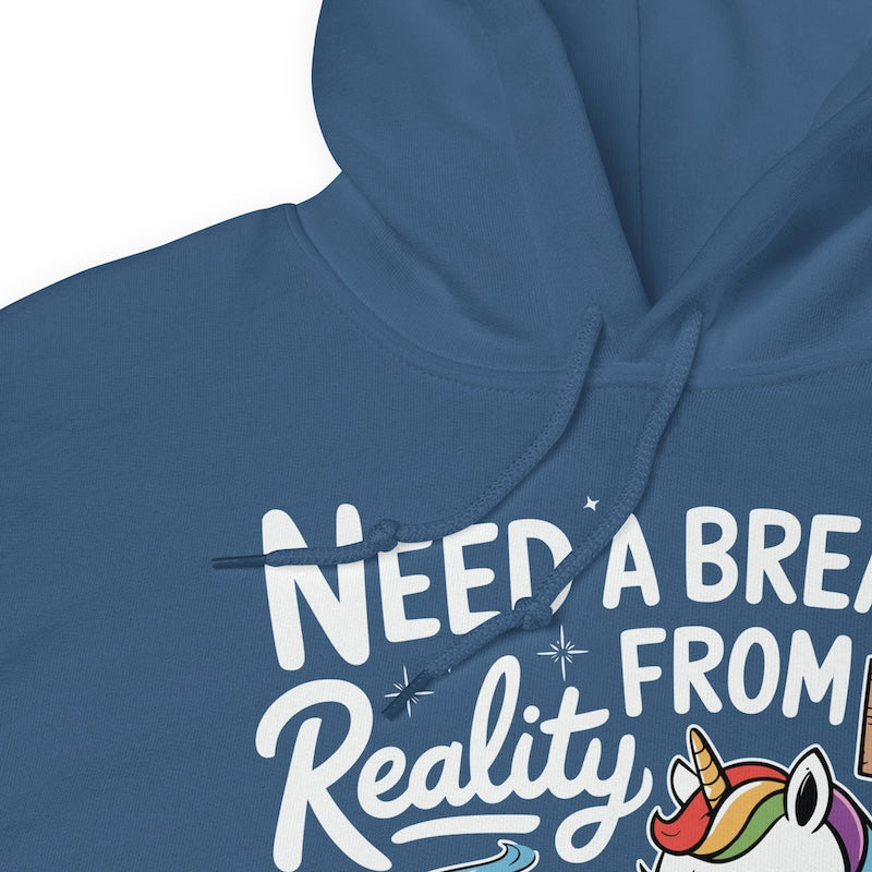 Blue hoodie with text 'NEED A BREAK FROM Reality' and a unicorn graphic on a white background
