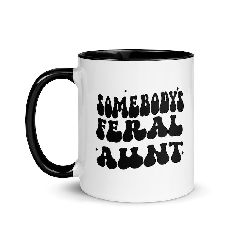 White mug with black text 'SOMEBODY'S FERAL AUNT' and black handle on a white background