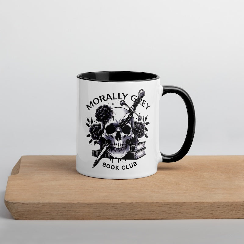 Mug with skull design and 'Morally Grey Book Club' text on a wooden surface.