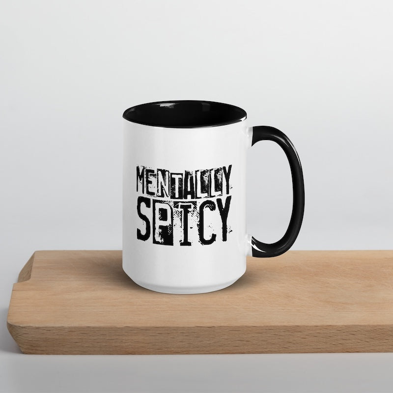 White mug with black handle and 'Mentally Spicy' text on a wooden surface.