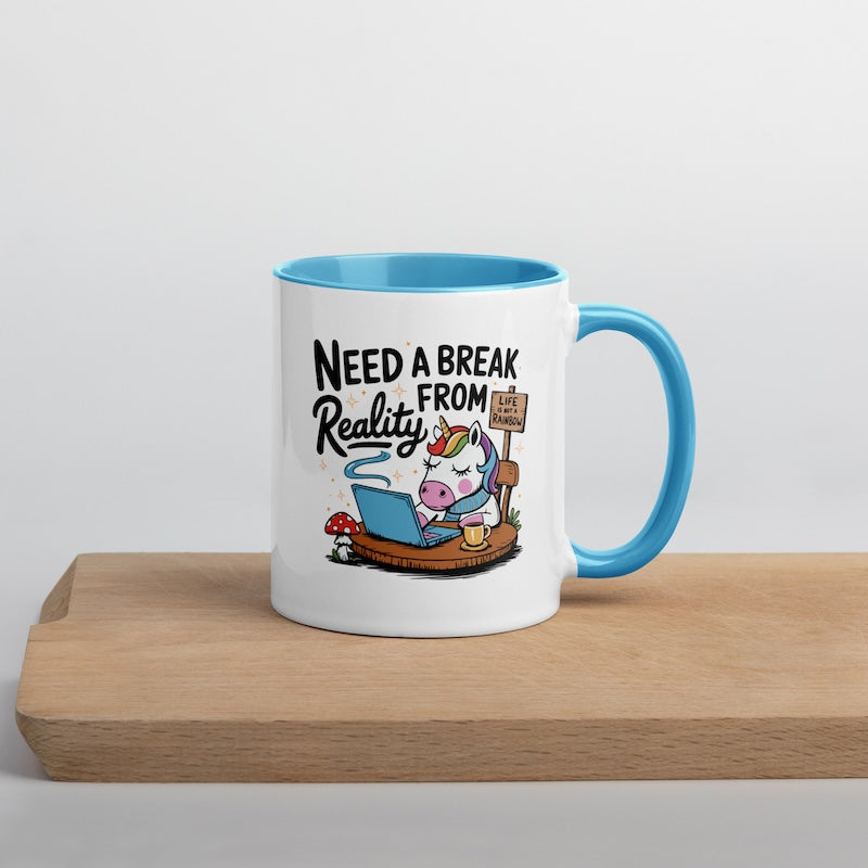 Mug with cartoon unicorn and text 'Need a Break from Reality' on a wooden surface.