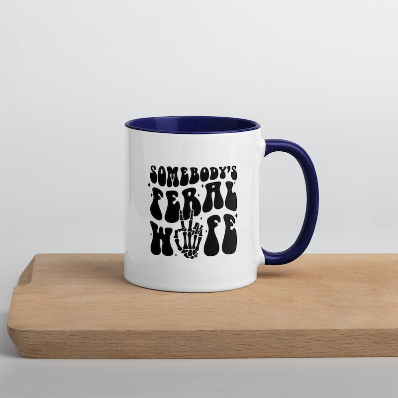 White mug with blue interior and handle, featuring black text on a wooden surface.