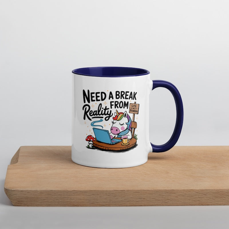 Mug with cartoon unicorn and text 'Need a Break from Reality' on a wooden surface.