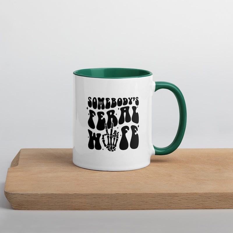 White mug with green interior and handle, featuring black text on a wooden surface.