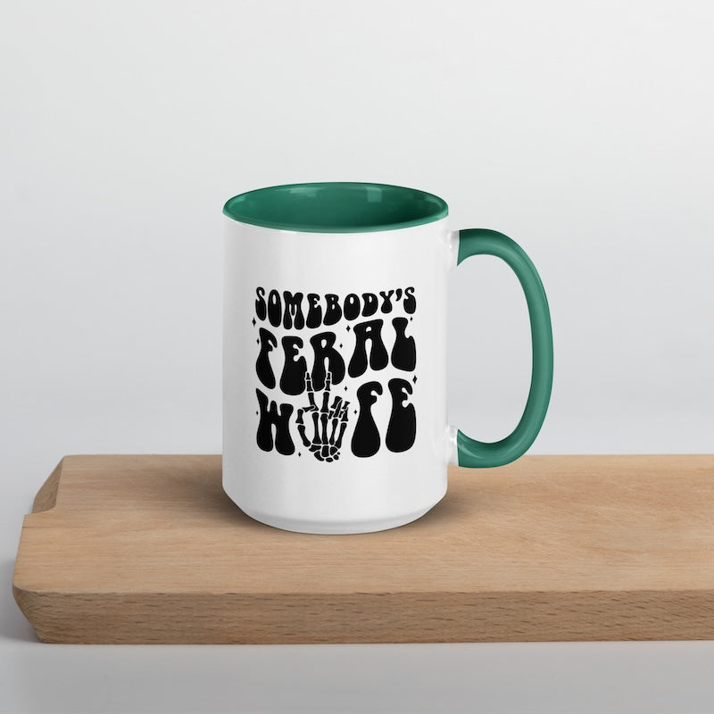 White mug with green interior and handle, featuring black text on a wooden surface.