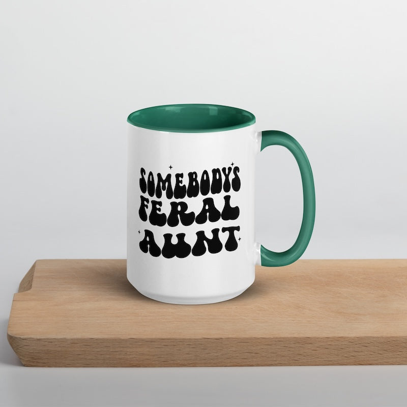 White mug with green interior and handle, featuring black text on a wooden surface.