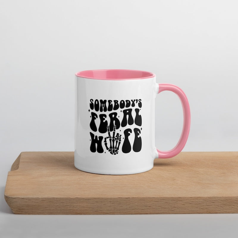 White mug with pink interior and handle, featuring black text on a wooden surface.