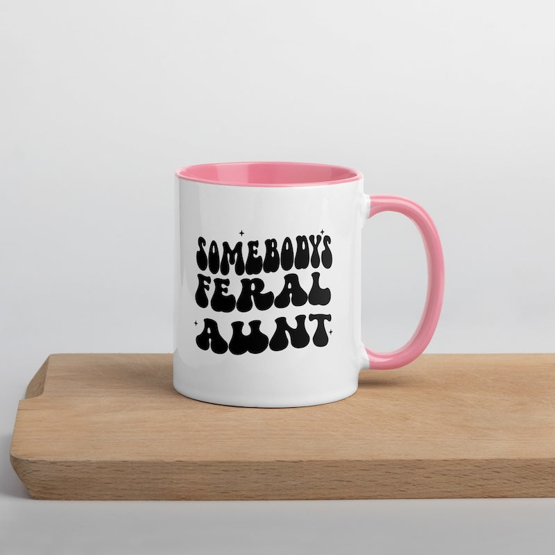 White mug with pink interior and handle, featuring black text on a wooden surface.