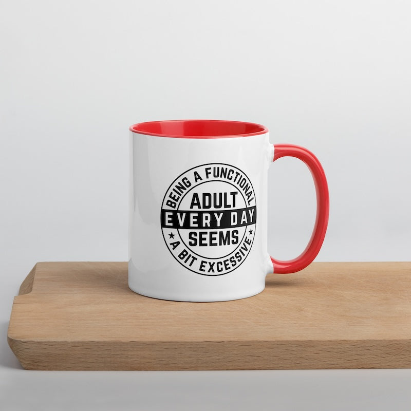 White mug with red interior and handle featuring a humorous quote on a wooden surface.