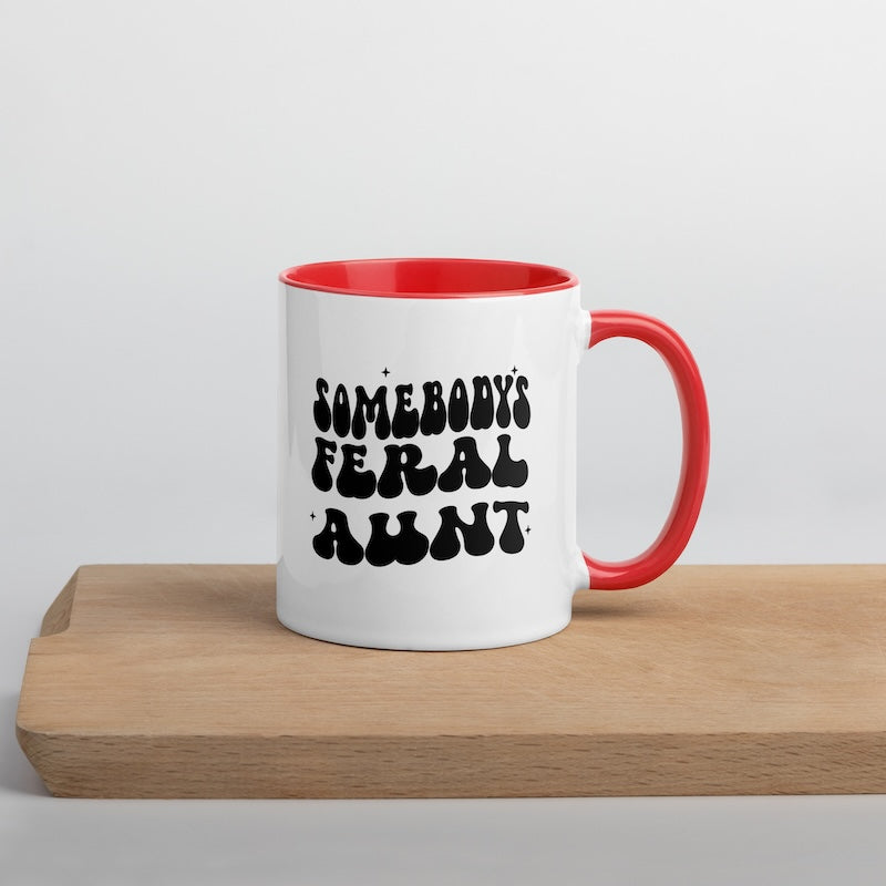 White mug with red interior and handle featuring black text on a wooden surface.