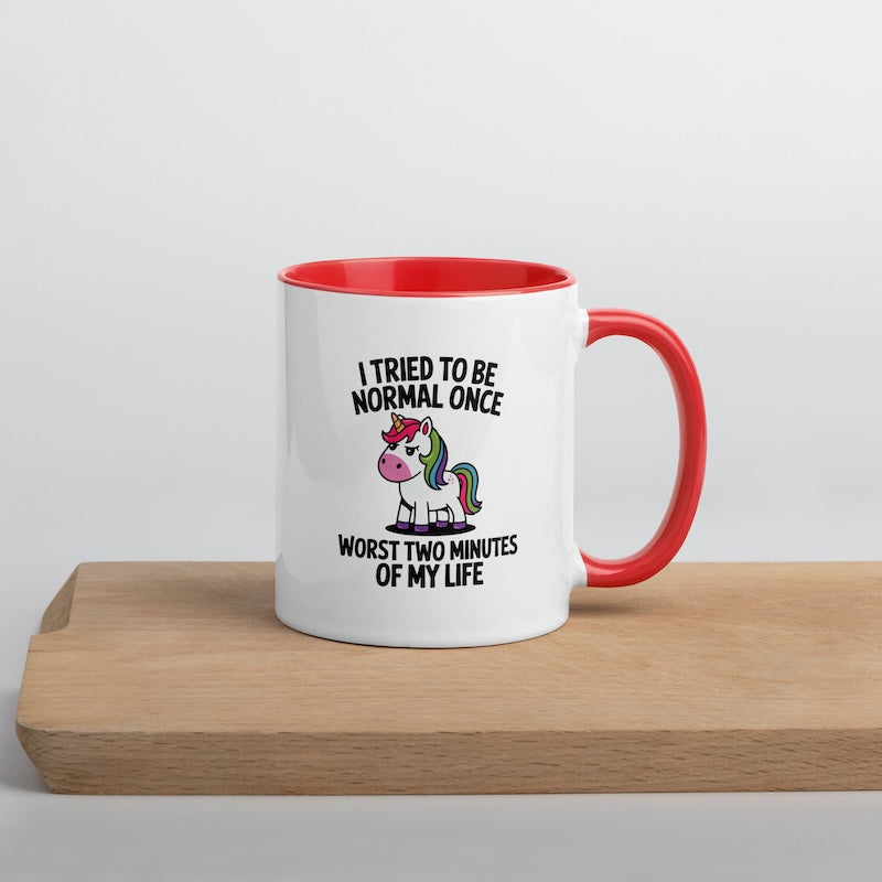 White mug with red interior and handle featuring a unicorn graphic and text on a wooden surface.
