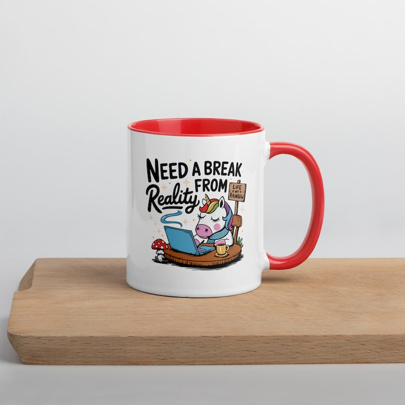 Mug with cartoon unicorn and text 'Need a Break from Reality' on a wooden surface.