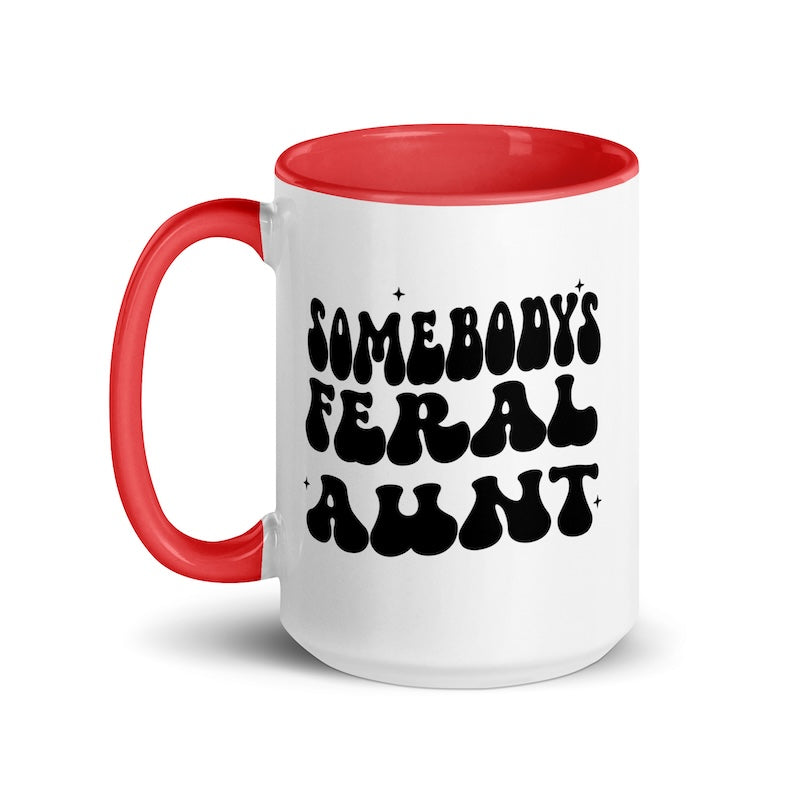 White mug with red handle and interior, featuring the text 'SOMEBODY'S FERAL AUNT' in black.