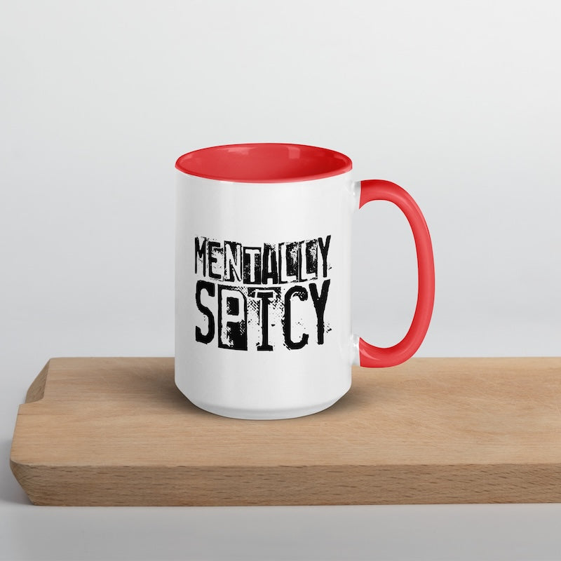 White mug with red interior and handle on a wooden surface, featuring the text 'Mentally Spicy'.