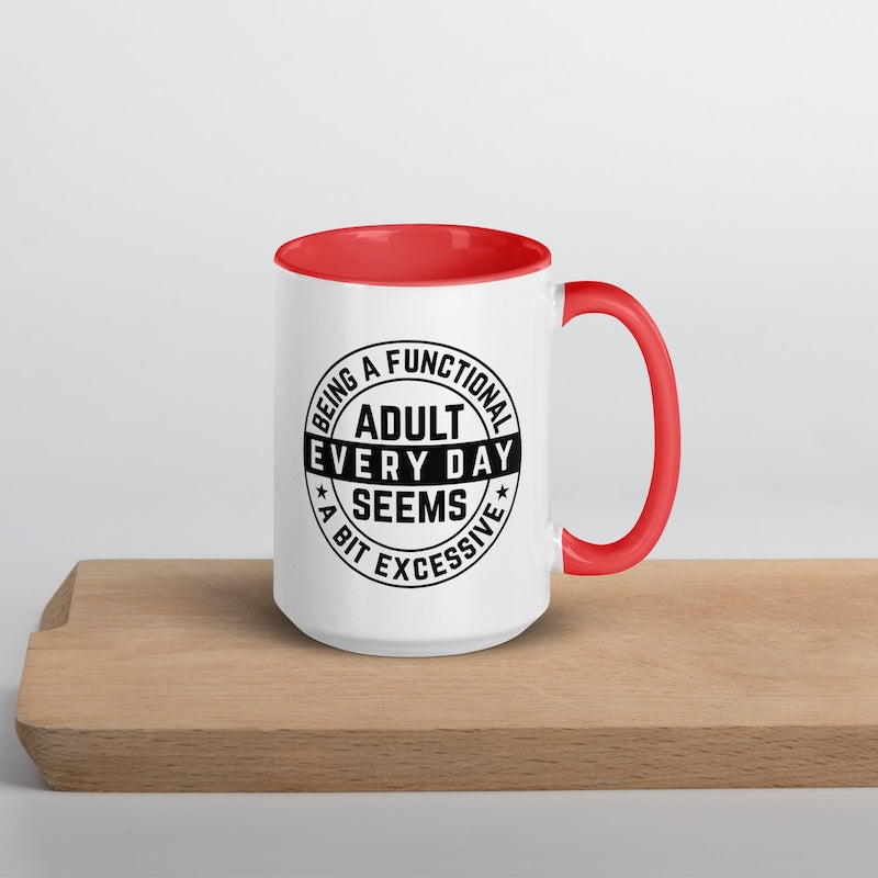 White mug with red interior and handle featuring a black text design on a wooden surface.