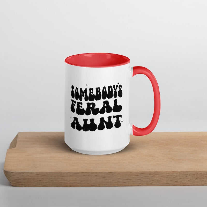 White mug with red interior and handle, featuring black text on a wooden surface.