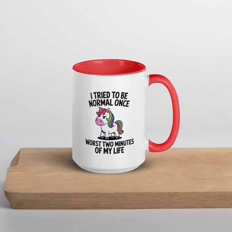 White mug with red interior and handle featuring a unicorn graphic and text on a wooden surface.