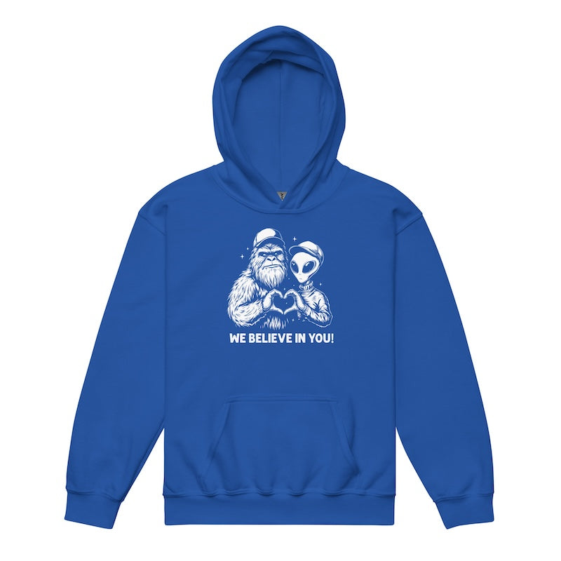 Blue hoodie with a graphic of a bearded figure and alien holding hands, with text 'WE BELIEVE IN YOU!' on a white background.