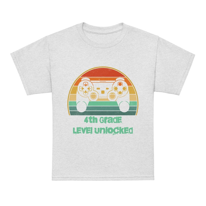 Gray t-shirt with a colorful graphic of game controllers and text '4th Grade Level Unlocked' on a white background